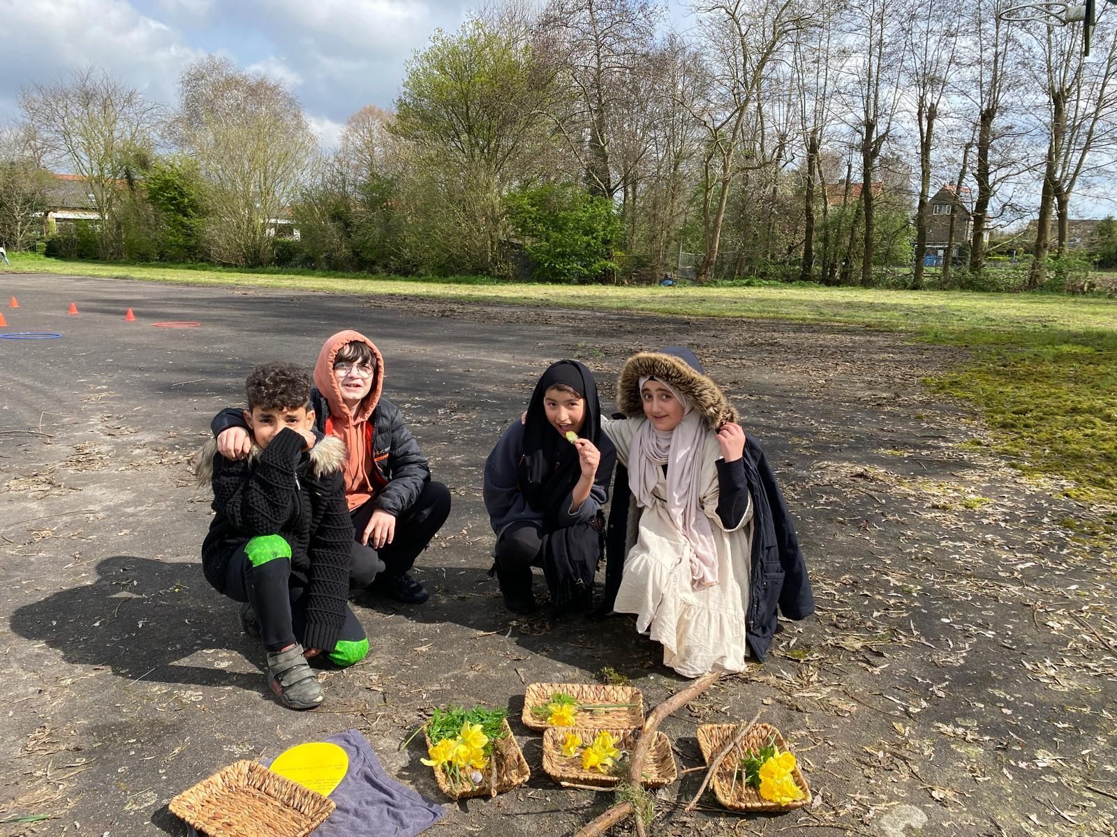 A group of children are sitting on the ground in a parking lot.