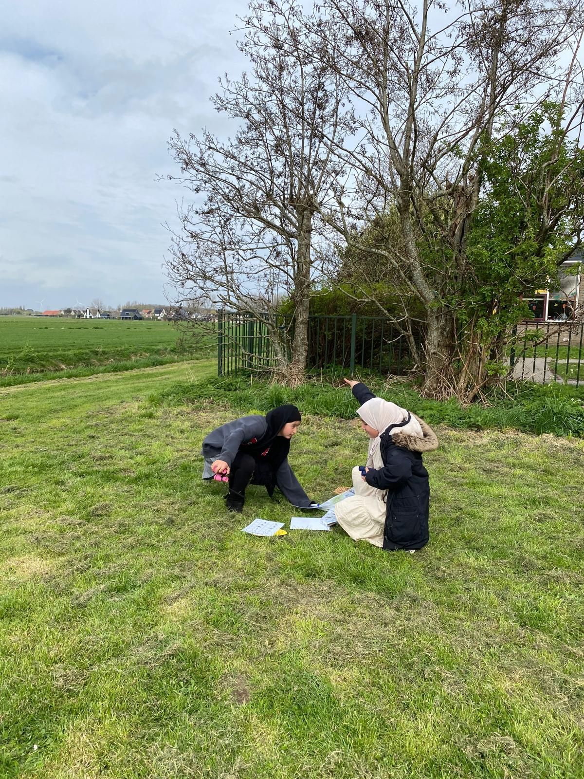 A couple of people are sitting on top of a lush green field.