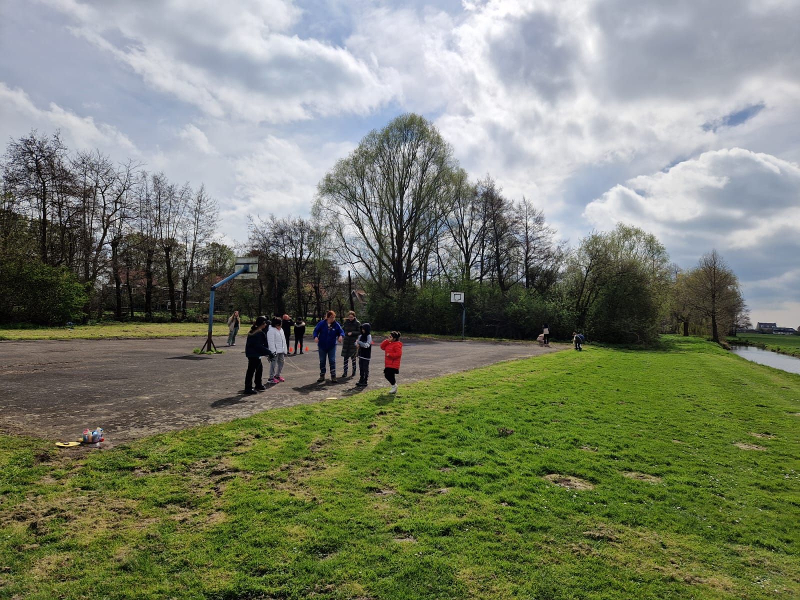 A group of people are standing in a field next to a river.