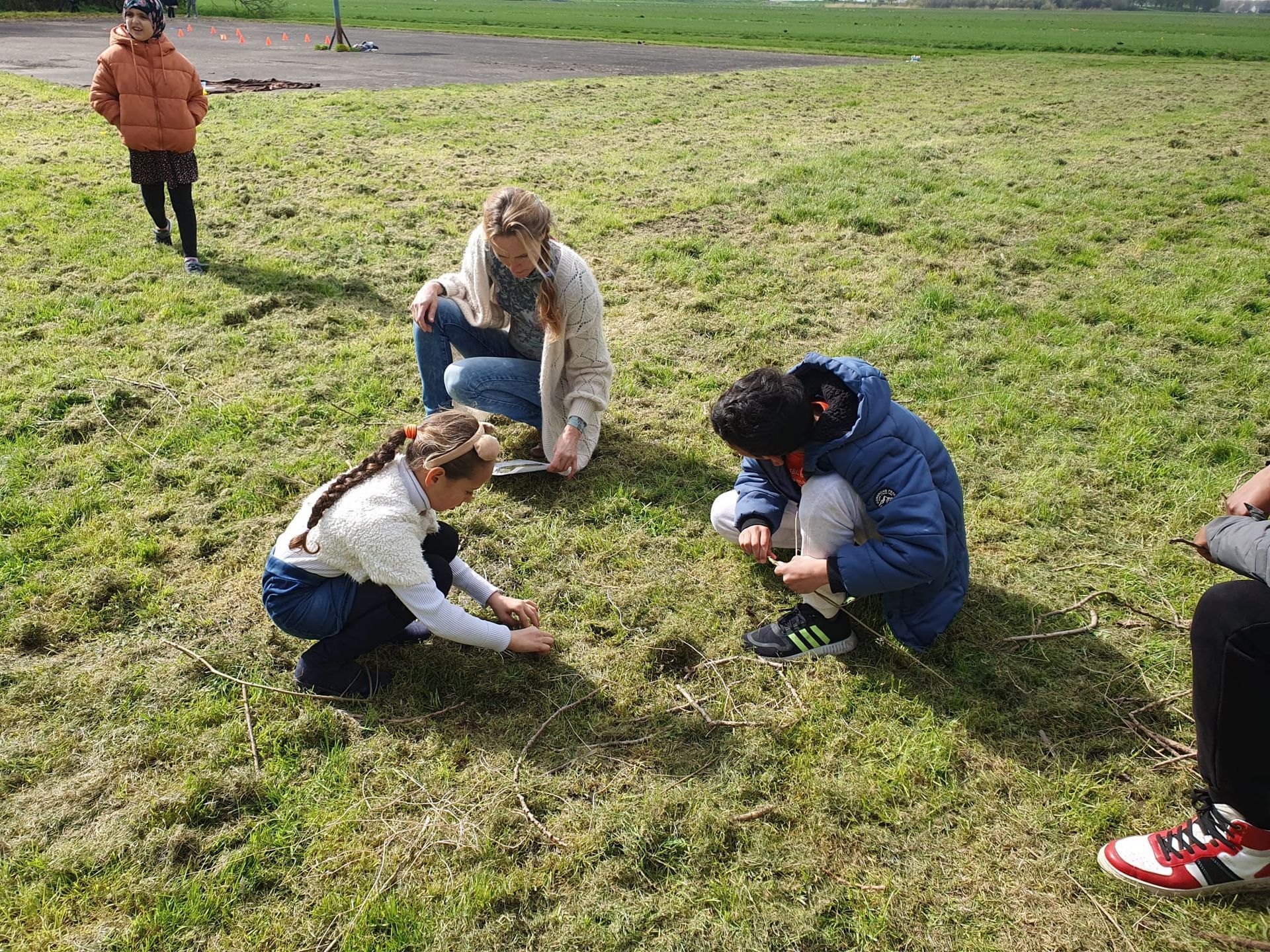 A person is kneeling down in a wooden box filled with dirt.
