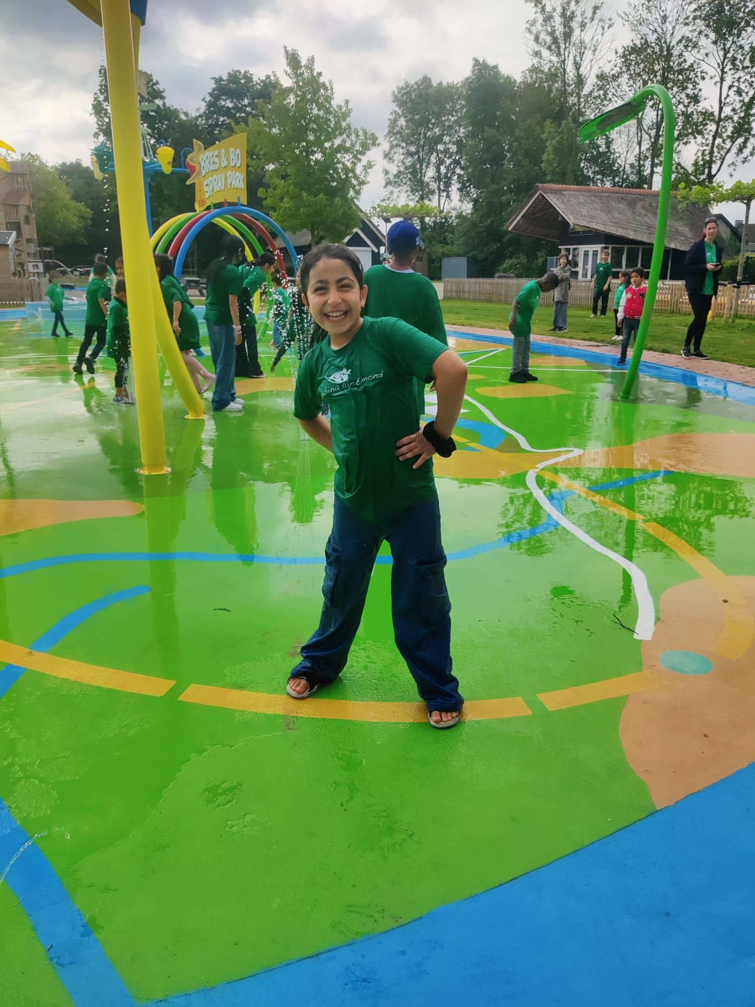 A young boy in a green shirt is standing in a water park.