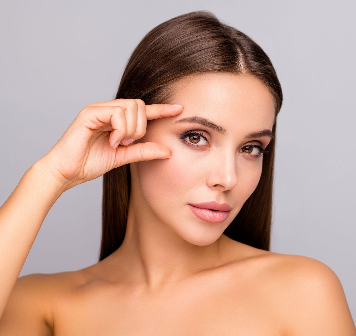 A woman is pointing at her eye with her finger.