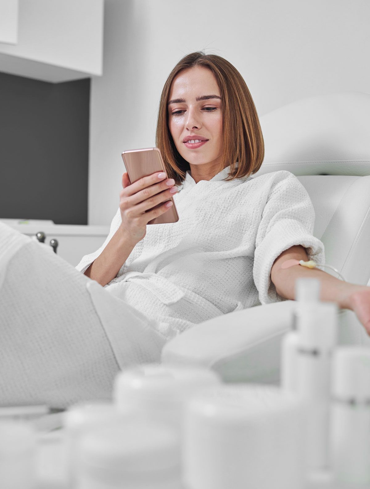 A woman is sitting in a chair looking at her phone.
