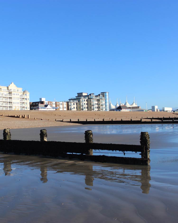 A view of Bognor Regis beach, from the calm sea at low tide  towards the  buildings along the Esplanade, including Butlin's  Resort.