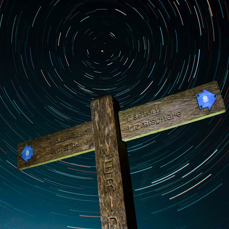 A wooden fingerpost for The South Downs Way against the night sky and stars. The National Park has been awarded Dark Skies status.