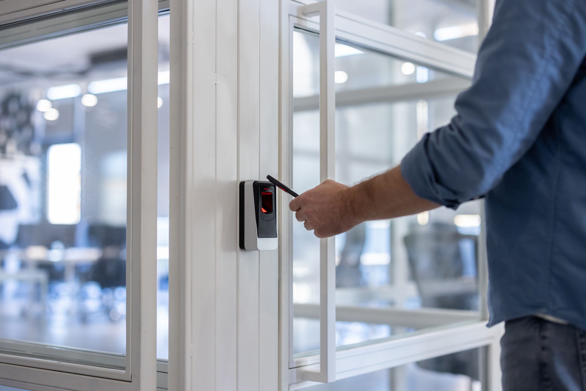 Person scanning key card on a sleek access control reader to unlock an office door.