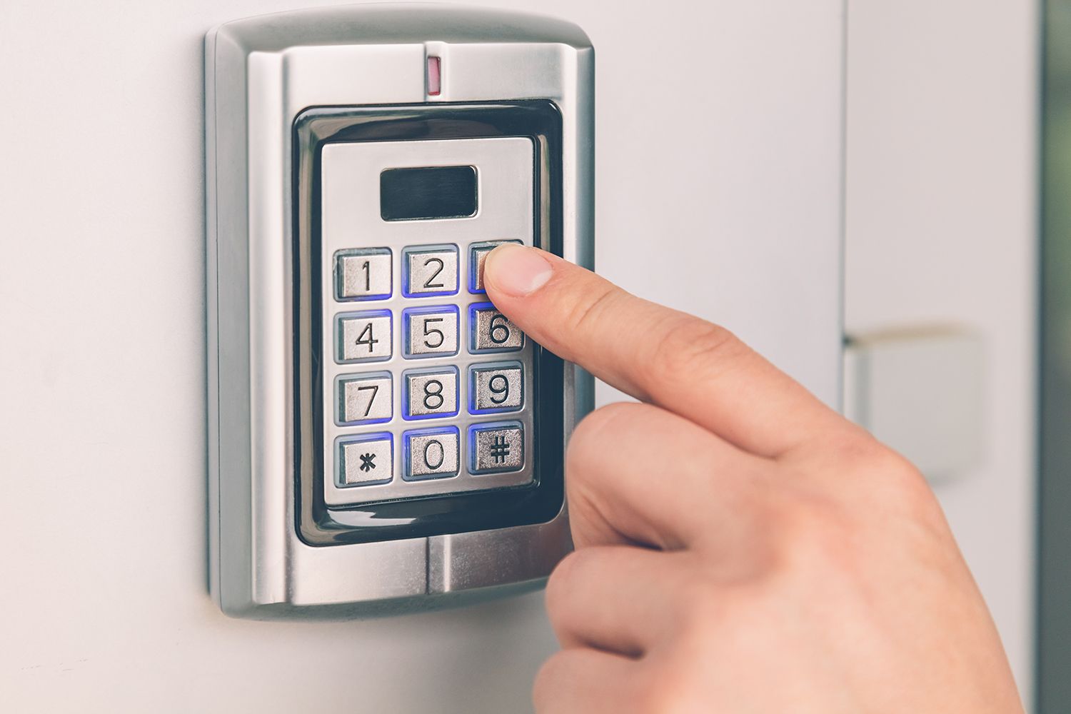 A hand is entering a security system code.