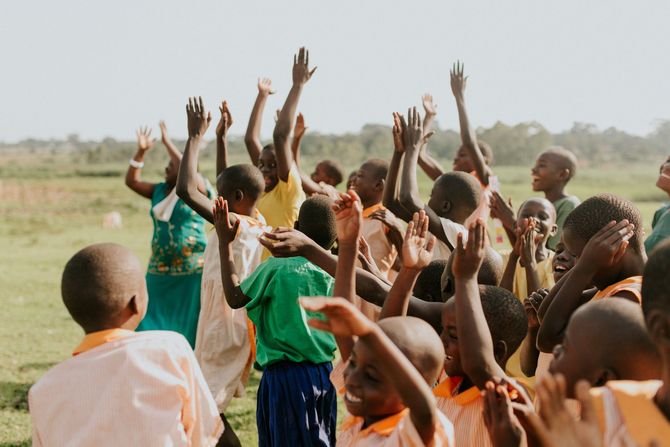 A group of children are raising their hands in the air