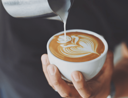 A person is pouring milk into a cup of coffee.