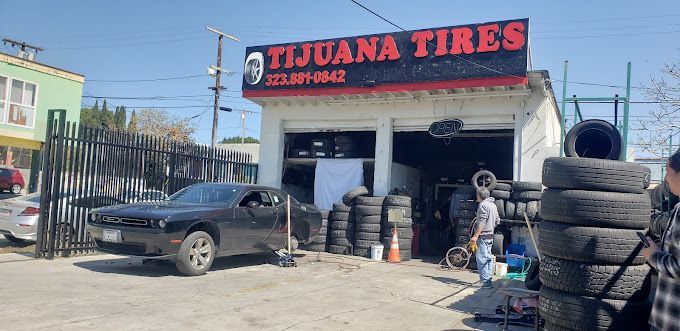 A car is parked in front of a tire shop.