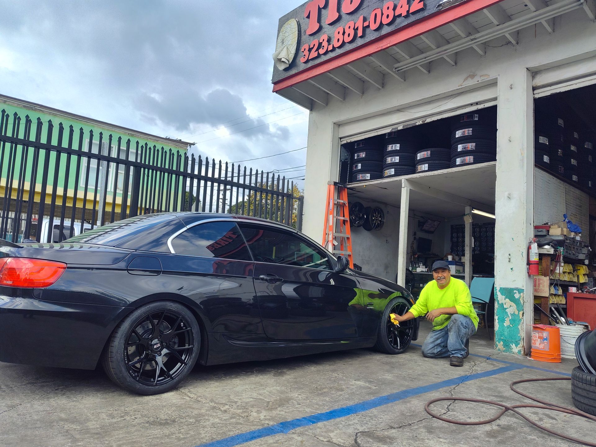 A man cleaning the tire of a black car.