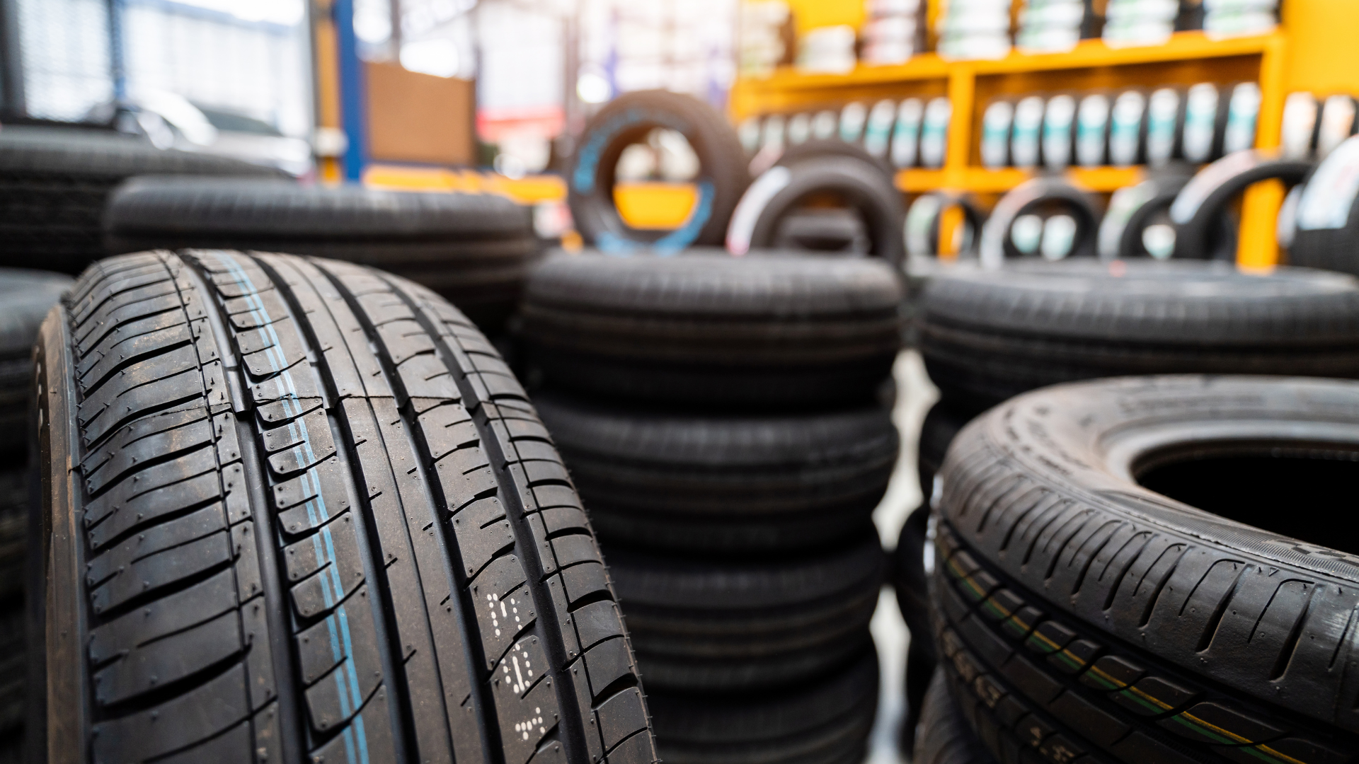 A bunch of tires are stacked on top of each other in a warehouse.