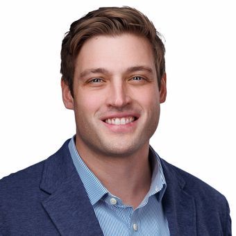 A man and a woman are sitting on a dock overlooking a lake.