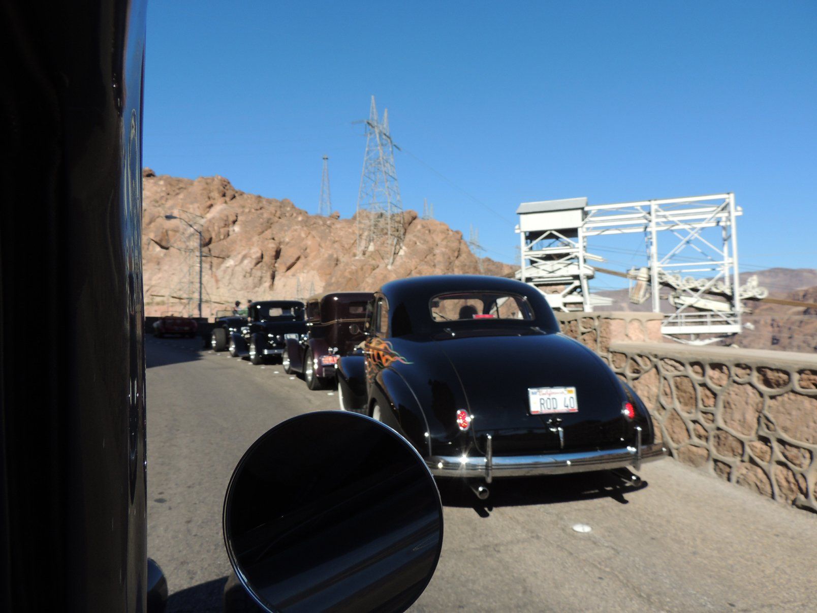 A row of old cars are parked on a road