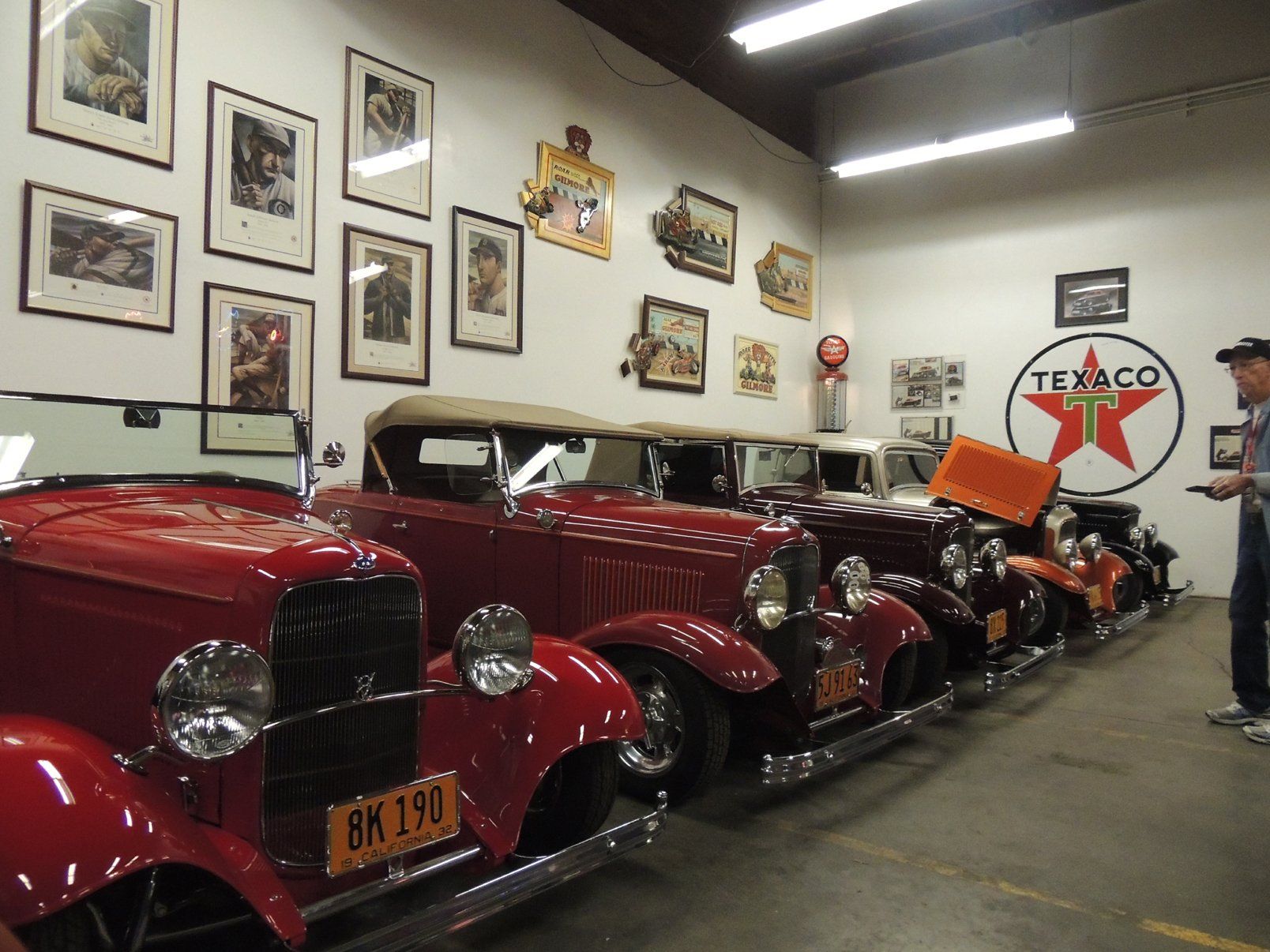 A row of old cars in a garage with a texaco sign on the wall