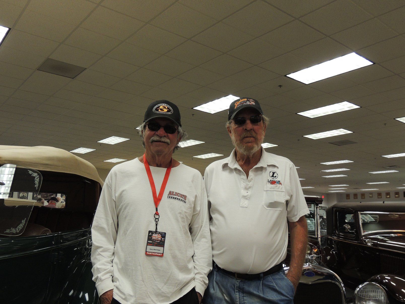 Two men are posing for a picture in front of a car
