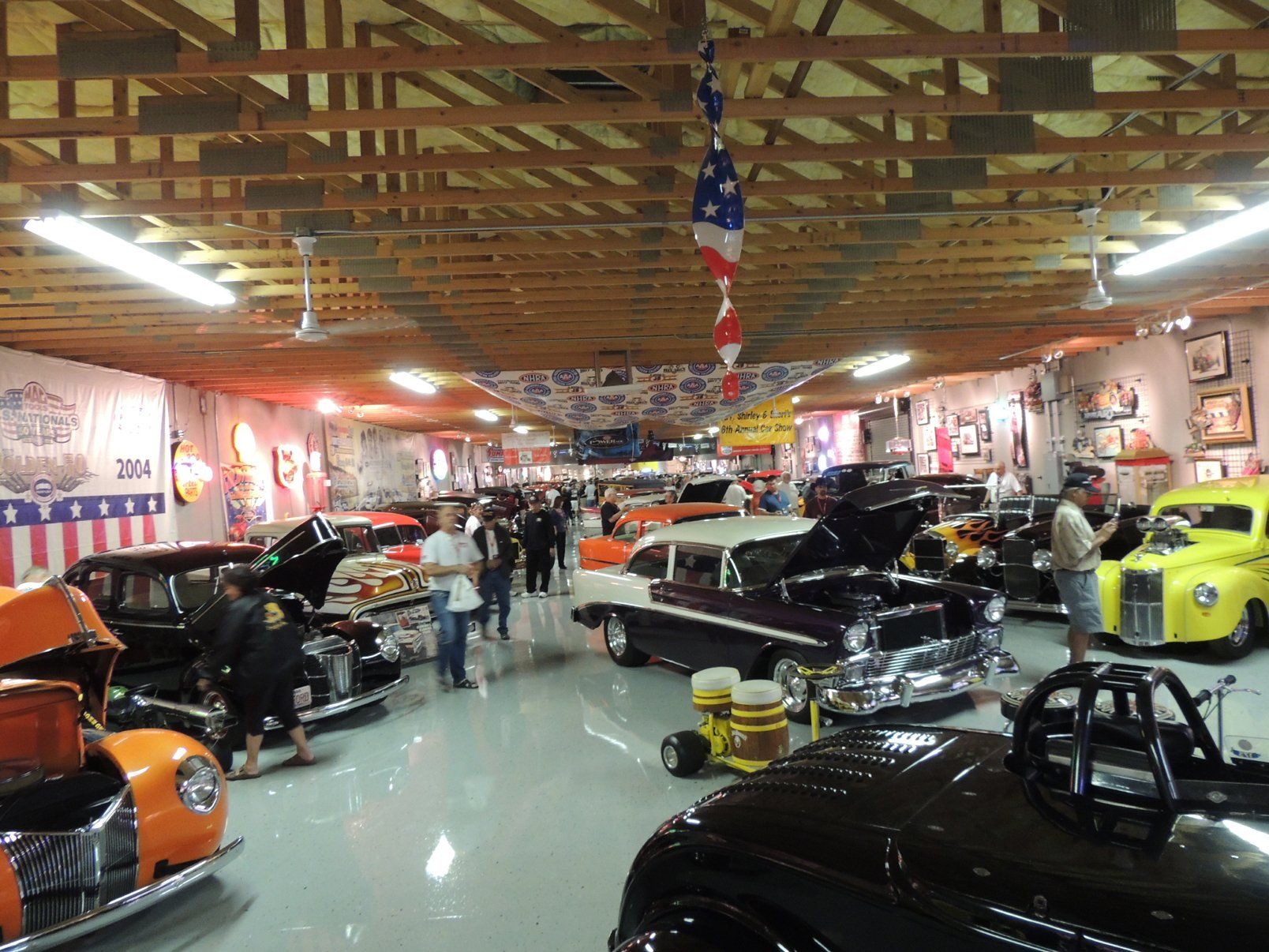 A garage filled with lots of old cars and people