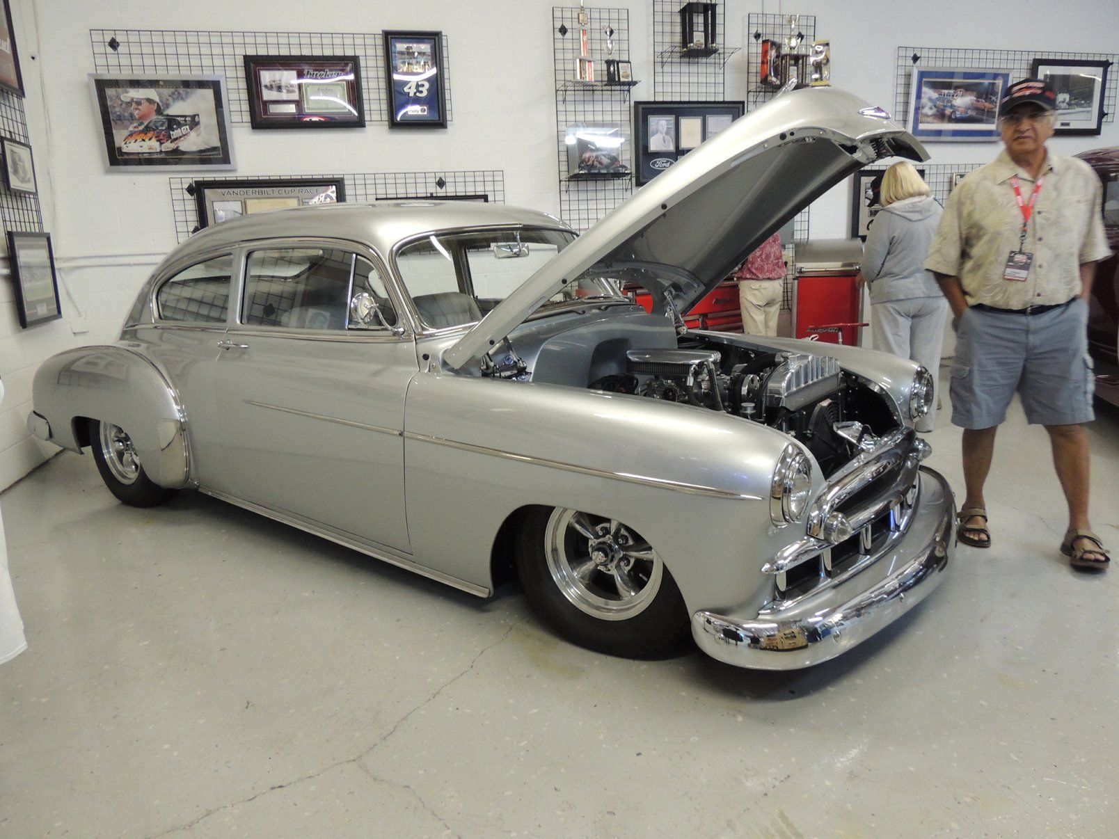 A man is standing next to a silver car with the hood up