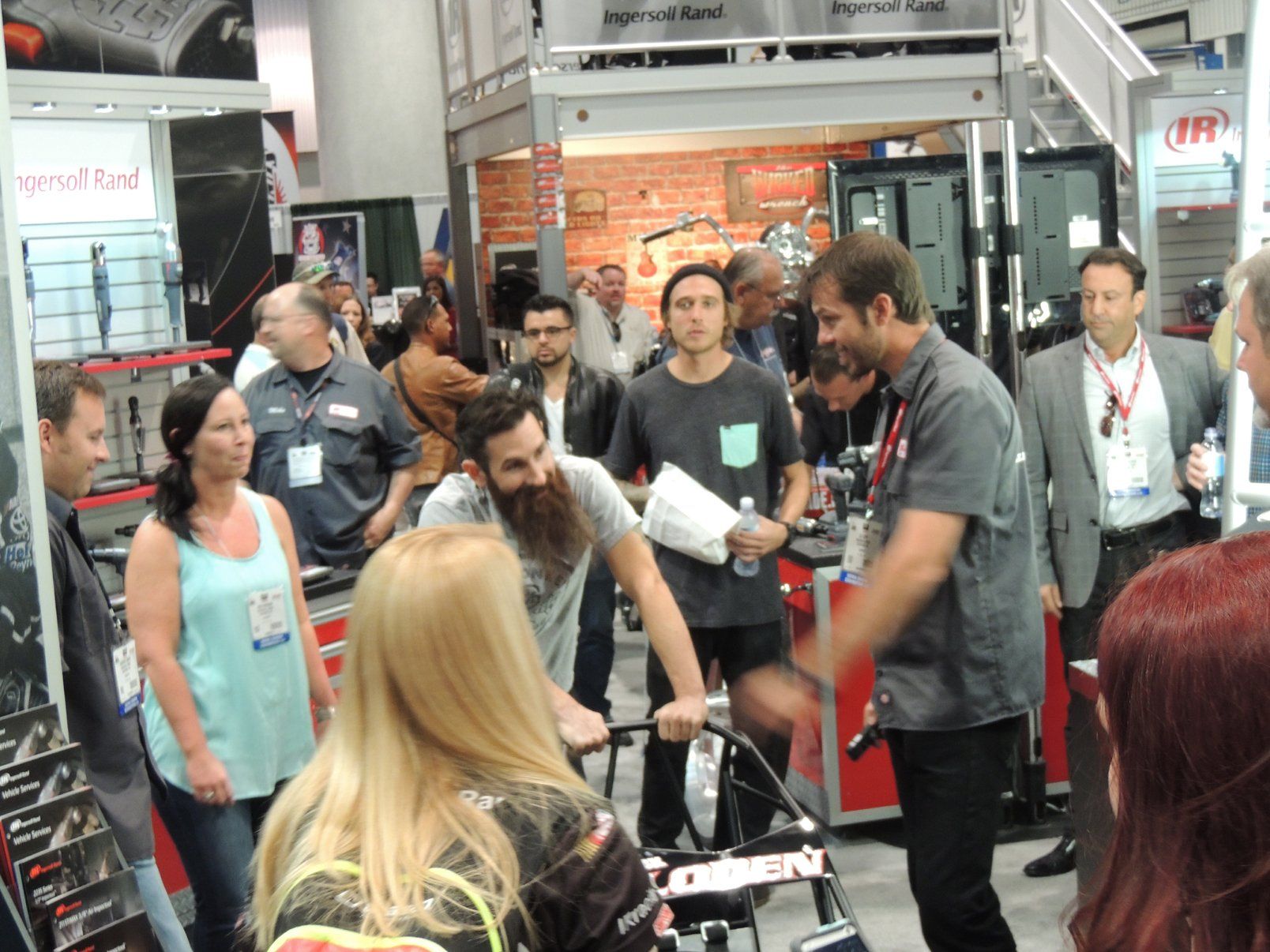 A group of people are gathered around a man in a walker