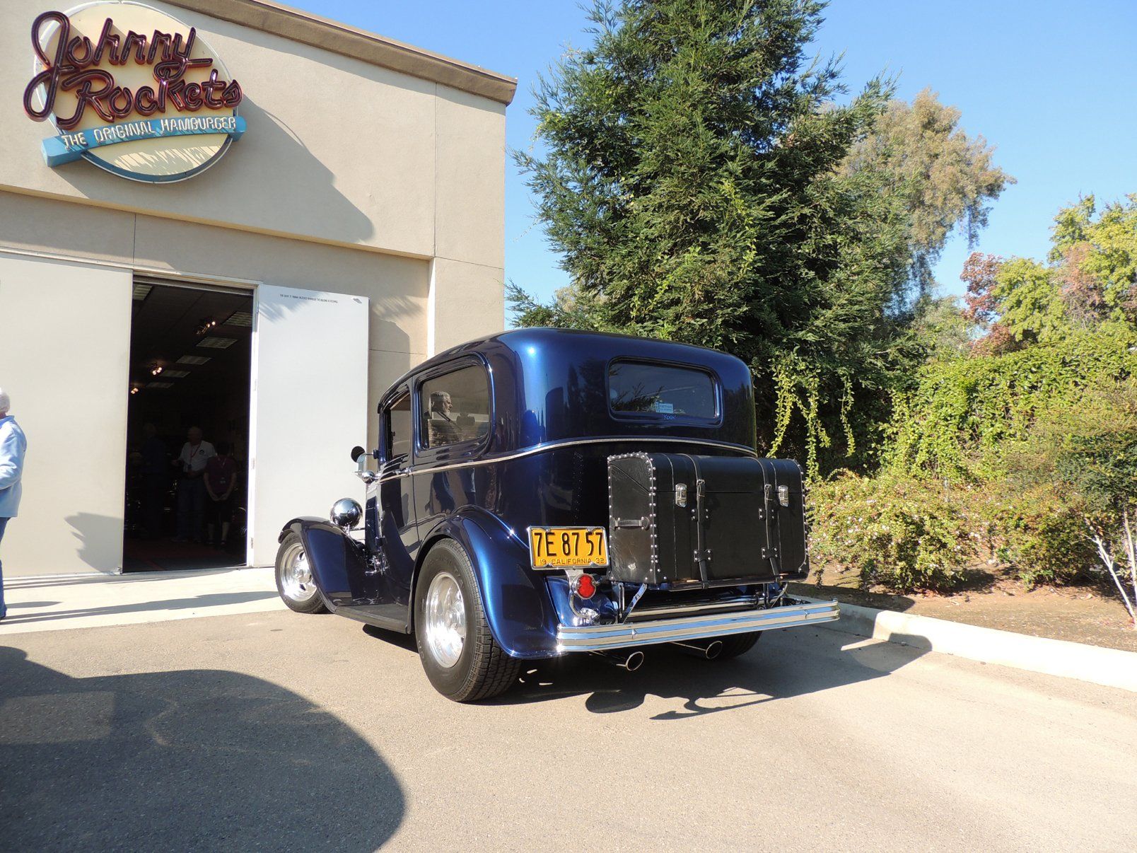 A blue car is parked in front of a building that says johnny 's
