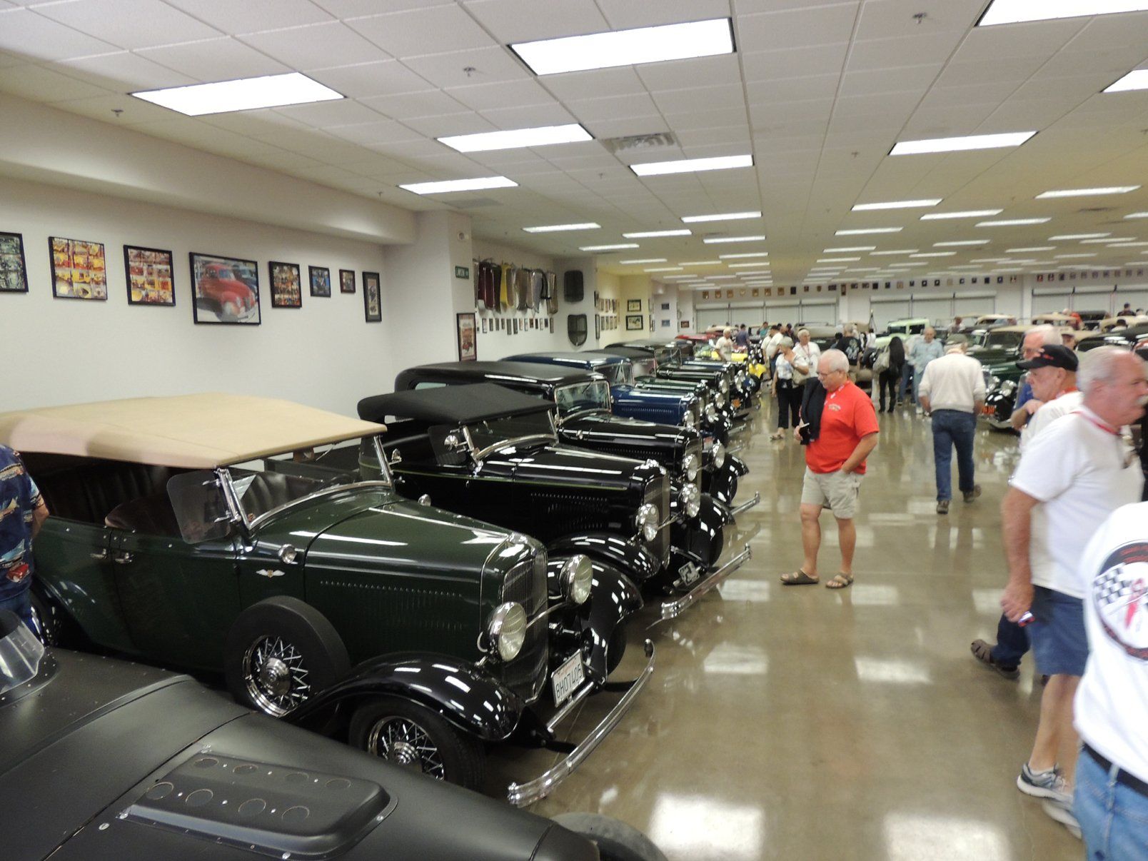 A group of people are looking at old cars in a museum