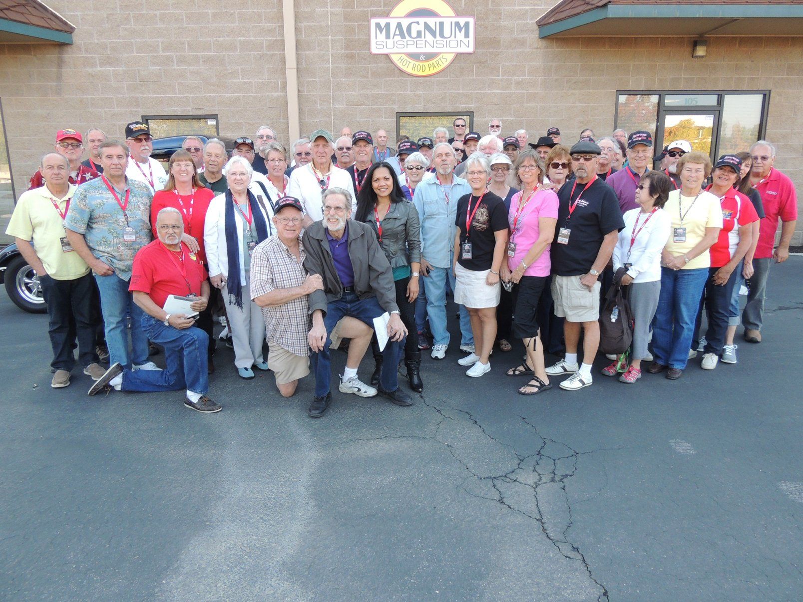 A group of people are posing for a picture in front of a building that says magnum
