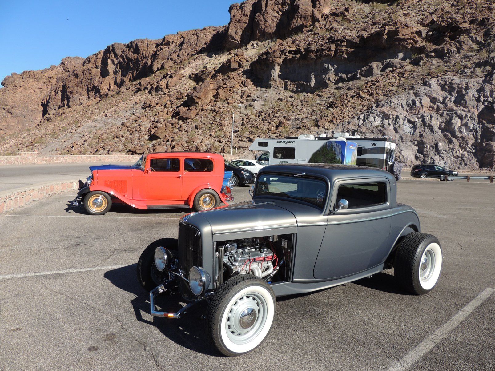 Two old cars are parked next to each other in a parking lot