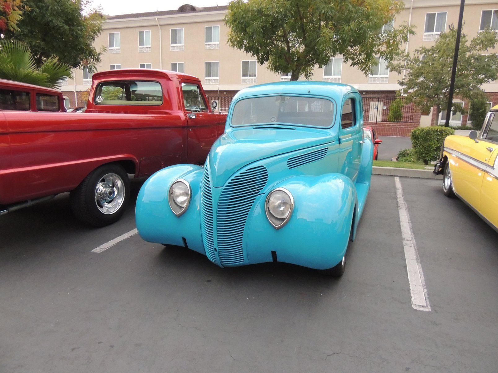 A blue car is parked next to a red truck in a parking lot