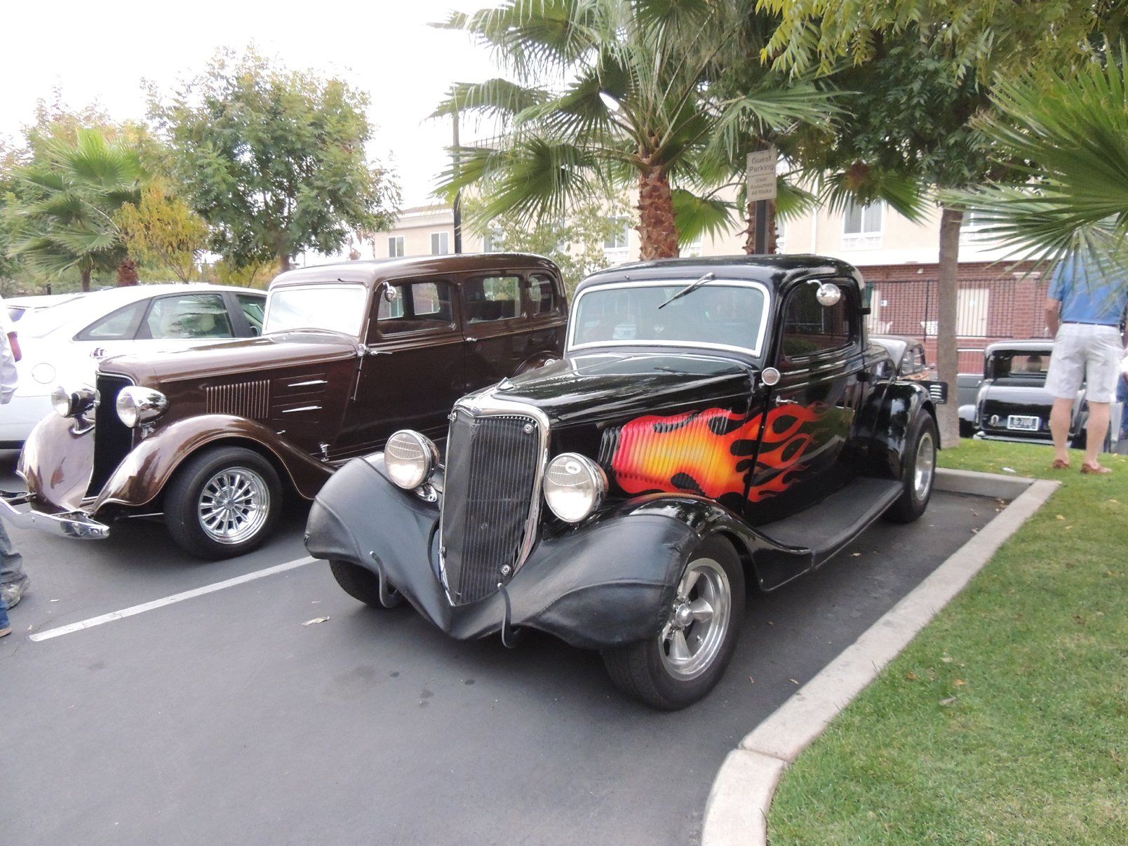 Two old cars are parked next to each other in a parking lot.