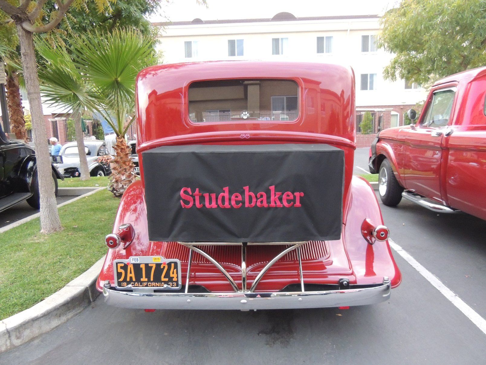 A red studebaker car is parked in a parking lot