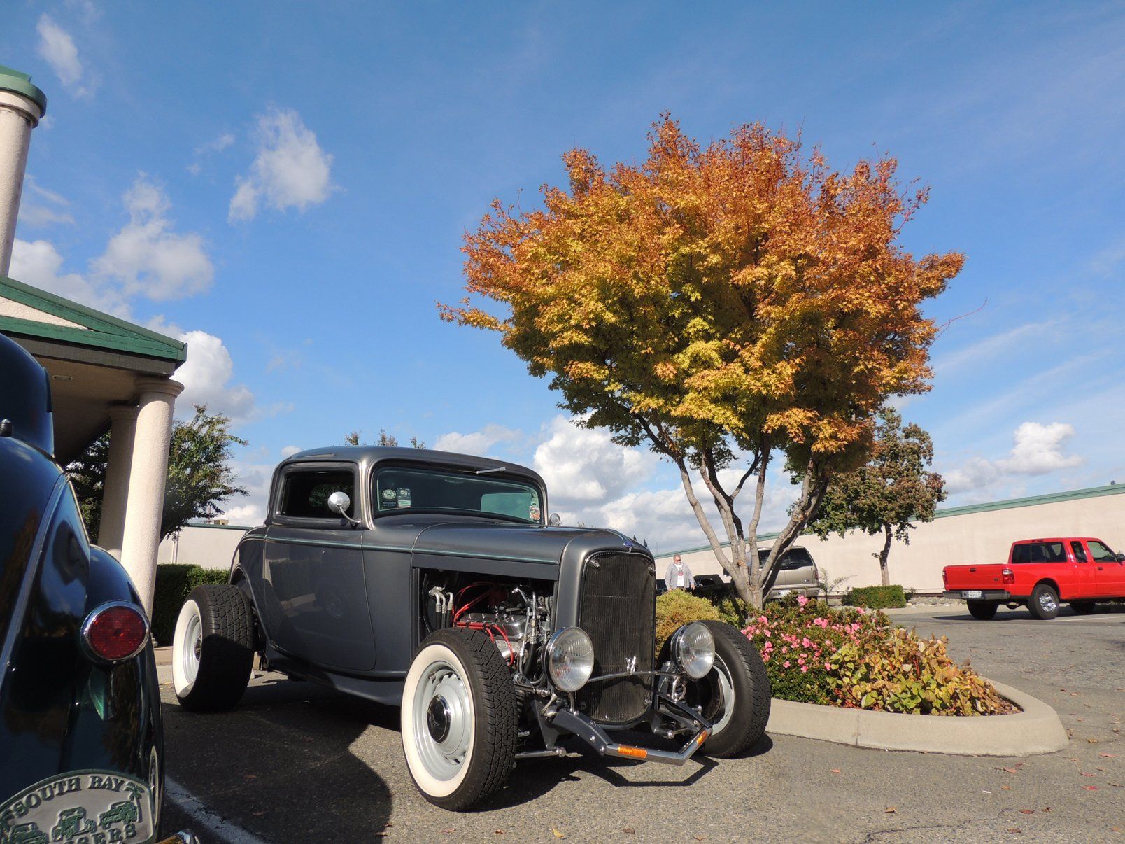 An old car is parked in front of a tree