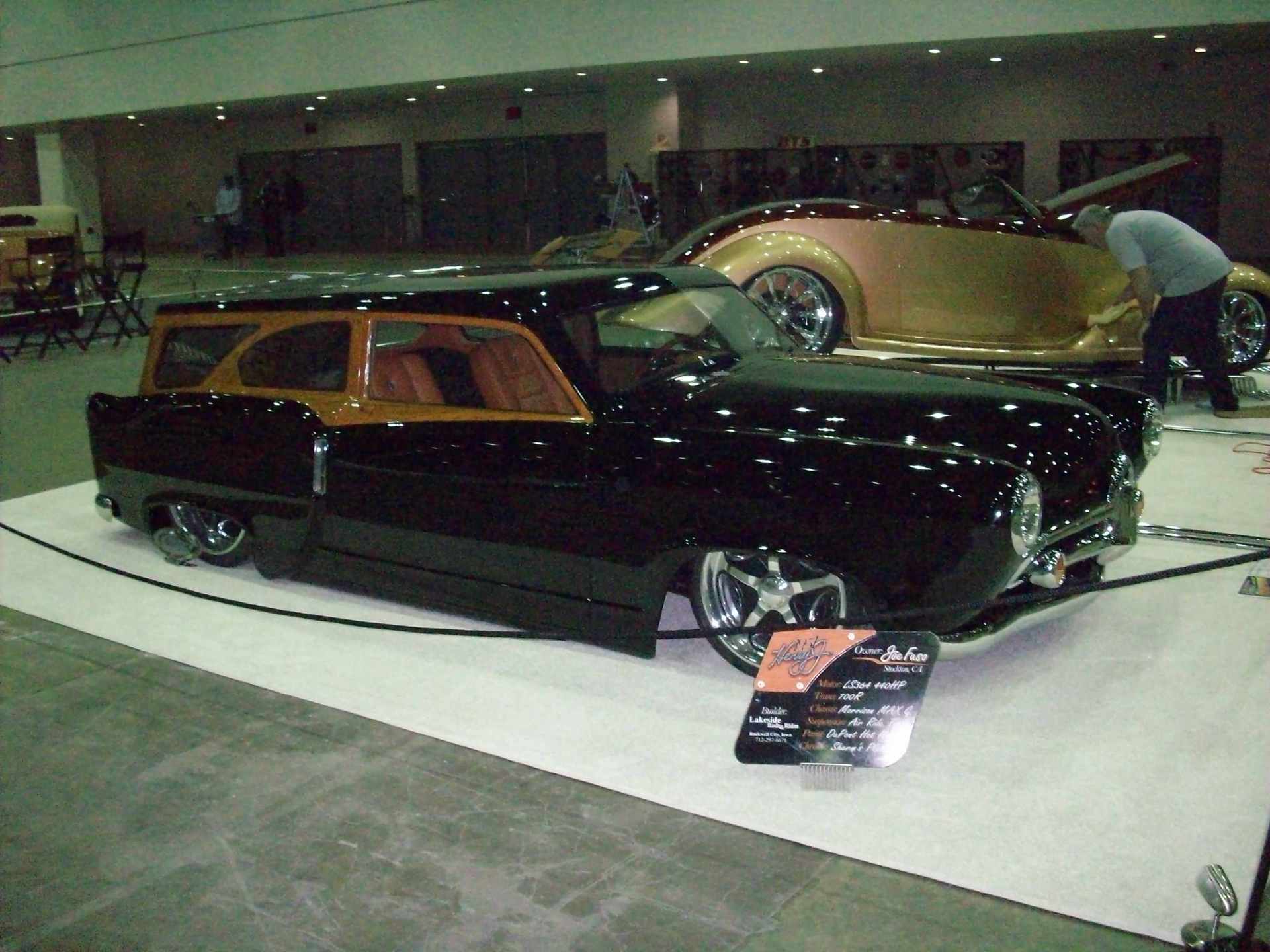 A black and gold car is on display at a car show