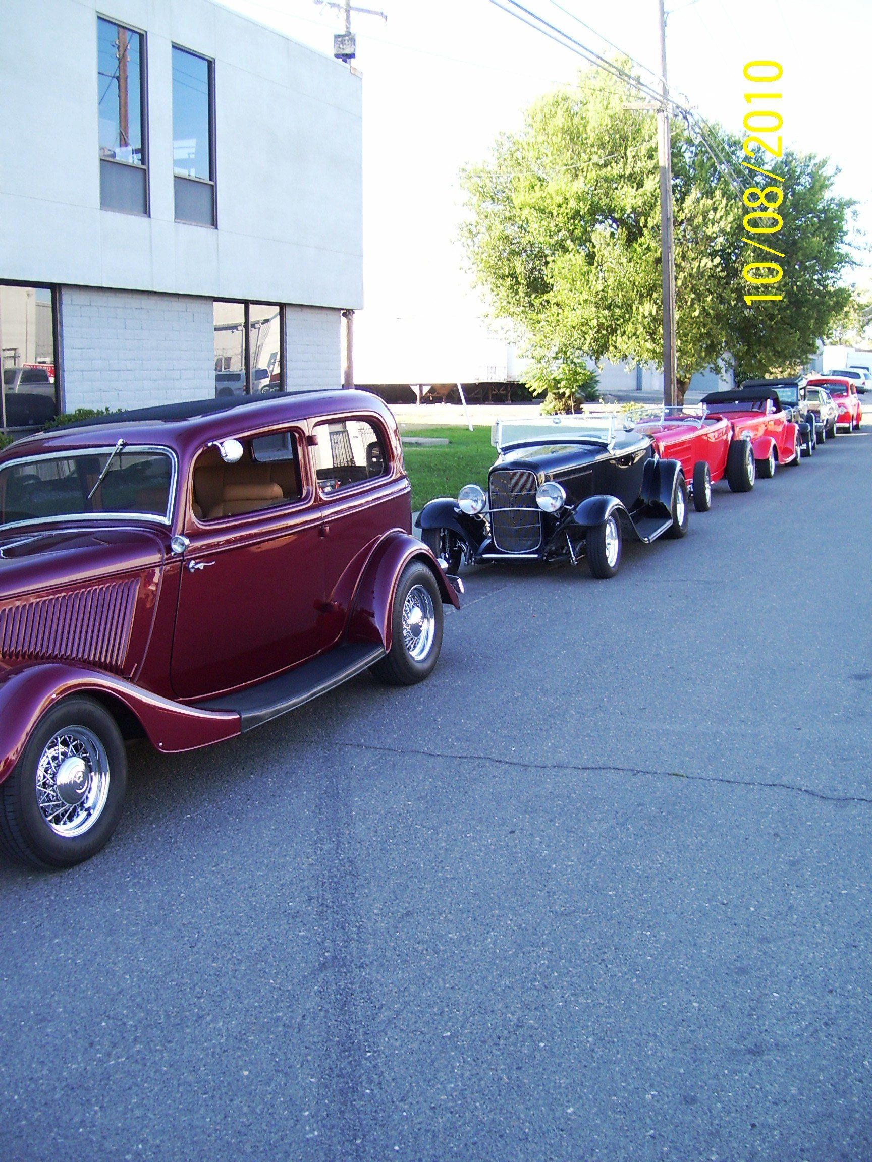 A row of old cars are parked on the side of the road