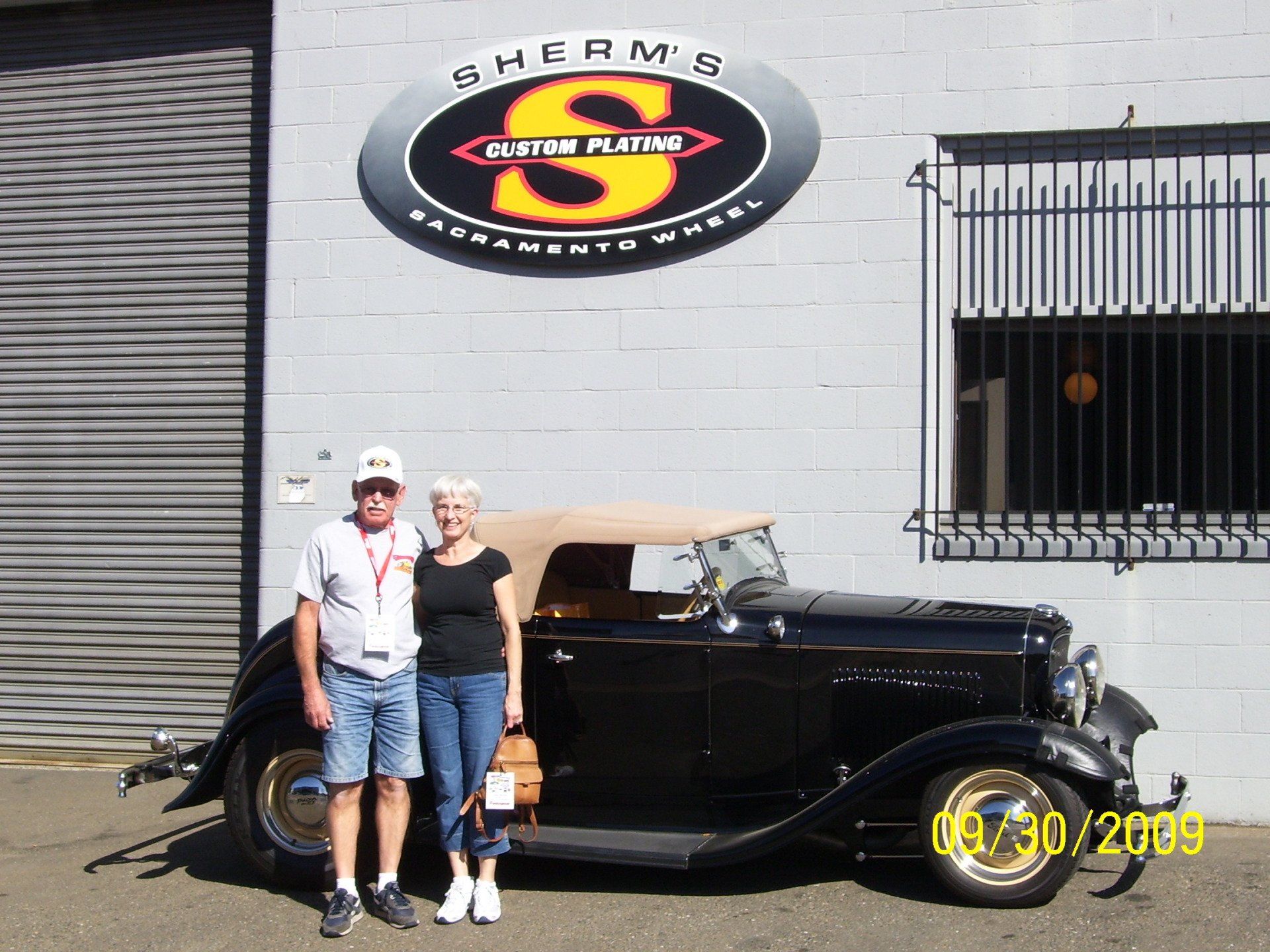 A man and woman standing in front of a sherman 's car