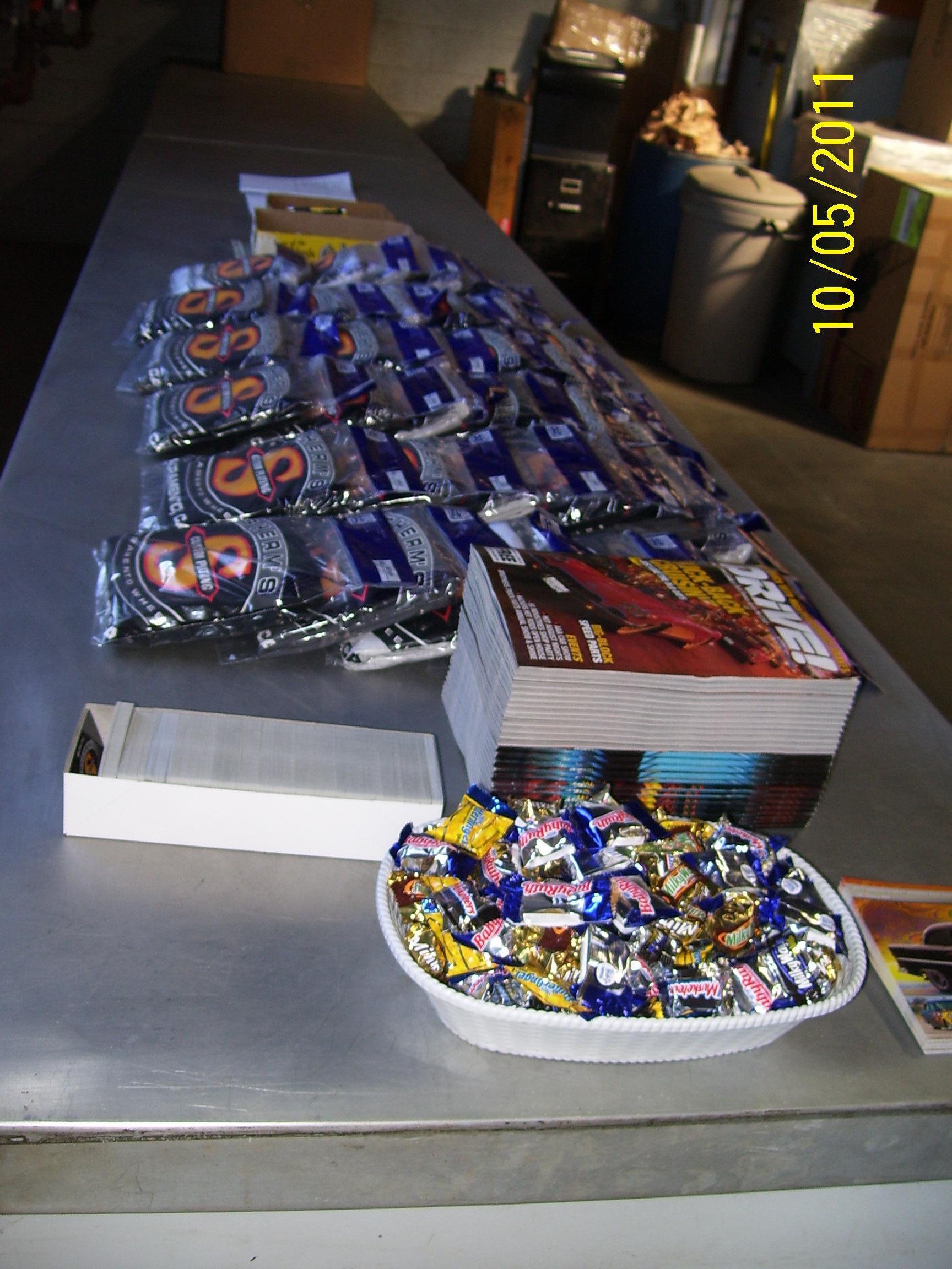 A table with a bowl of candy and a stack of magazines on it