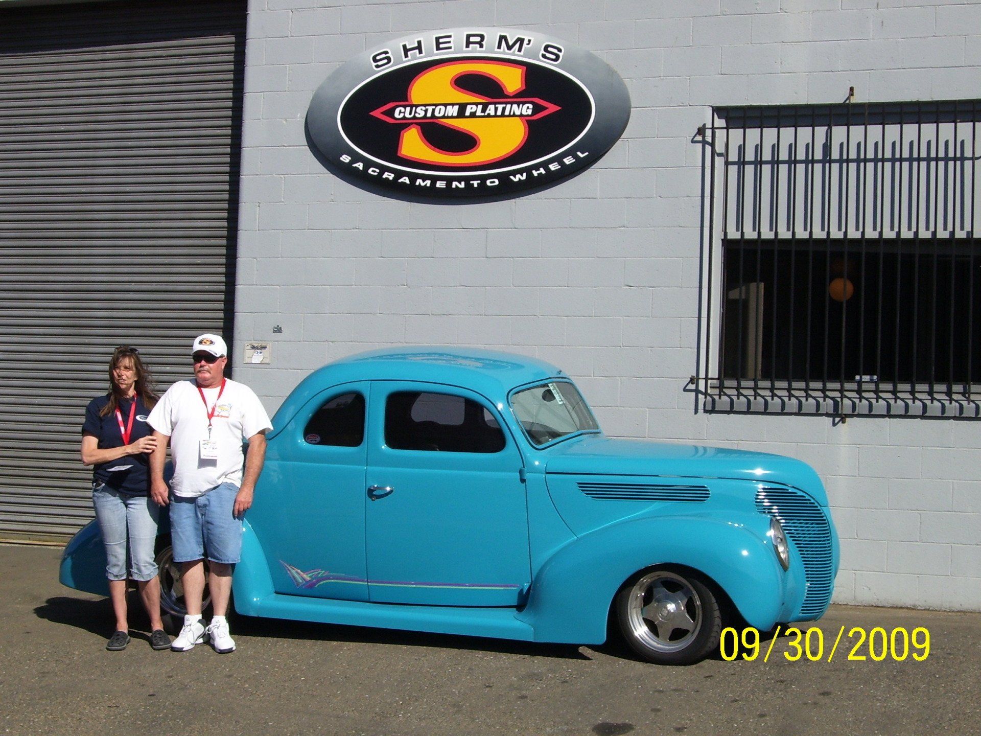 A blue car is parked in front of a building with the letter s on it