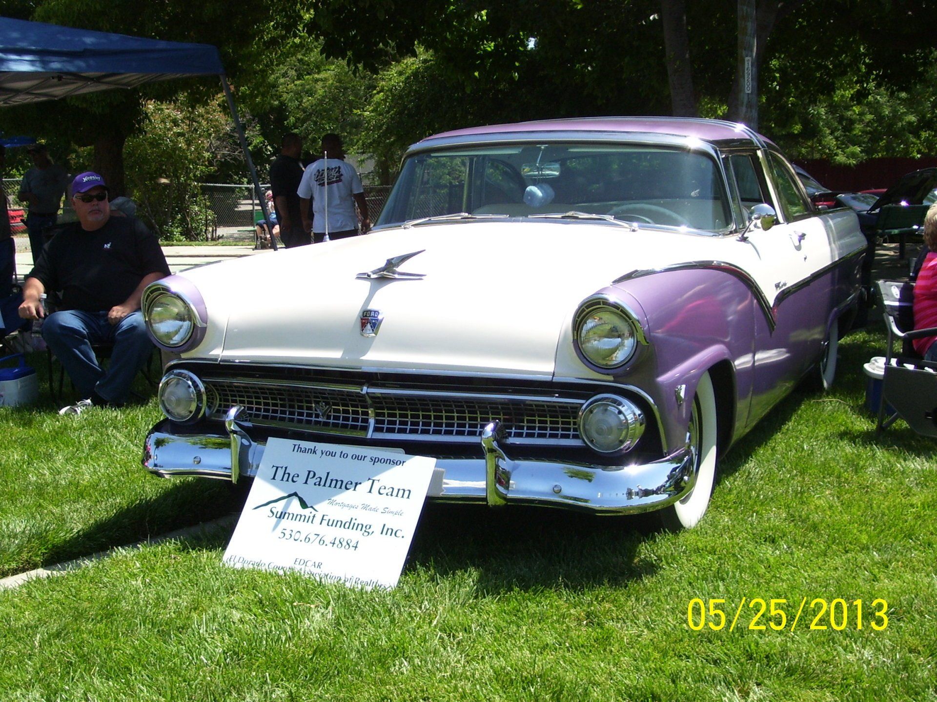 A purple and white ford car is parked in the grass