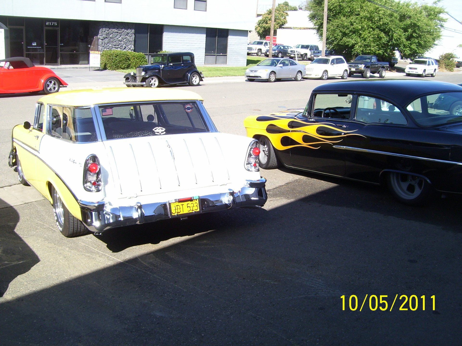 A yellow and white car is parked next to a black car