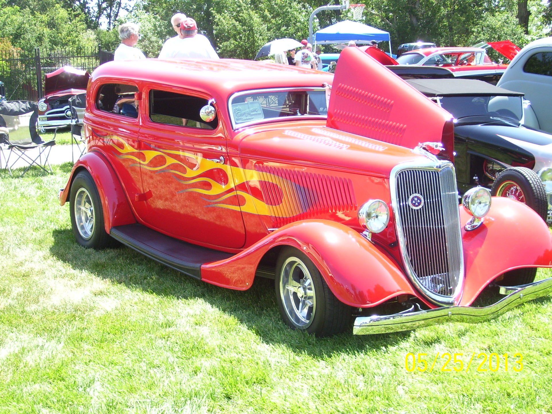 A red car with flames painted on it is parked in the grass