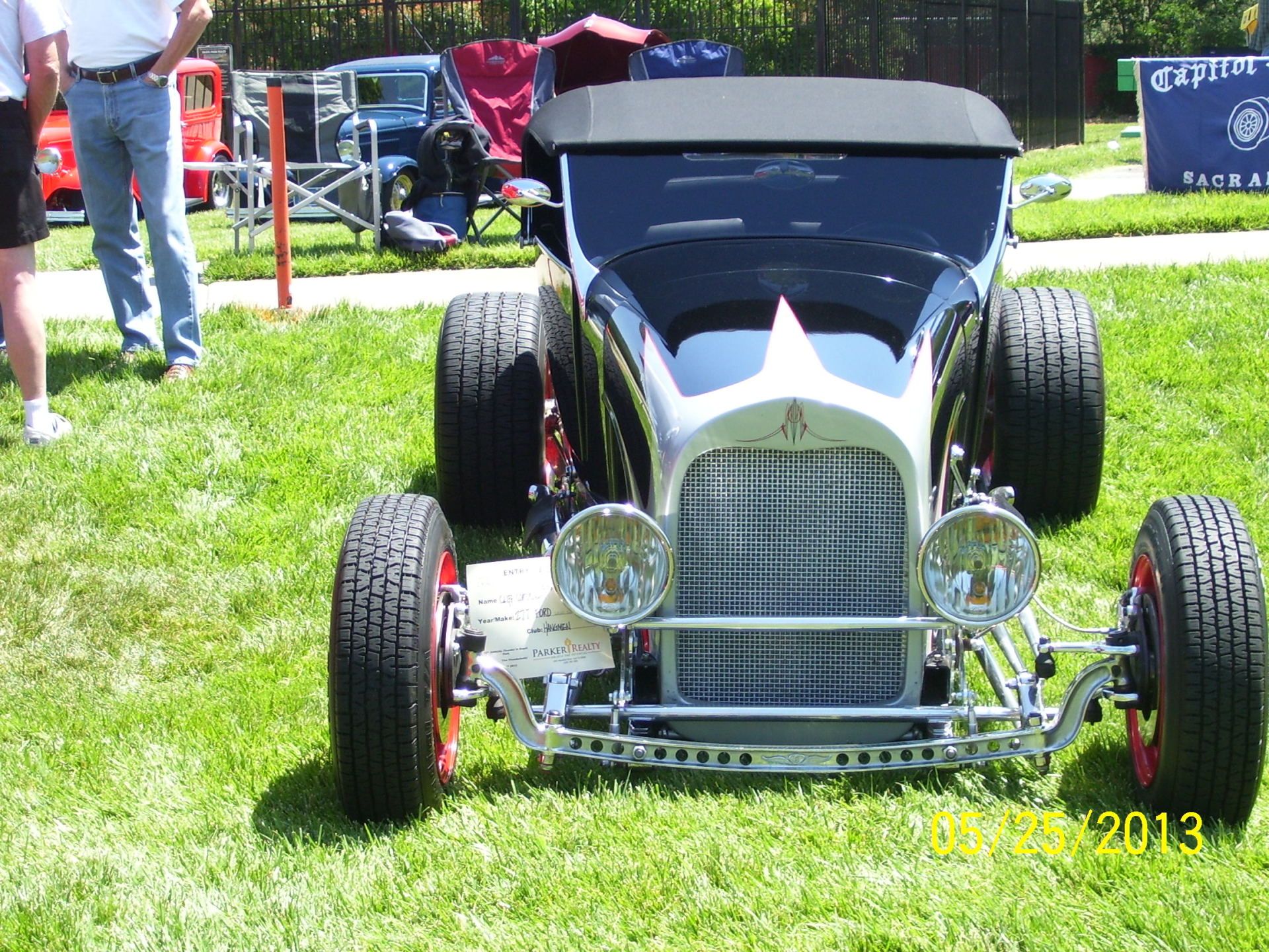A black and white hot rod is parked in the grass