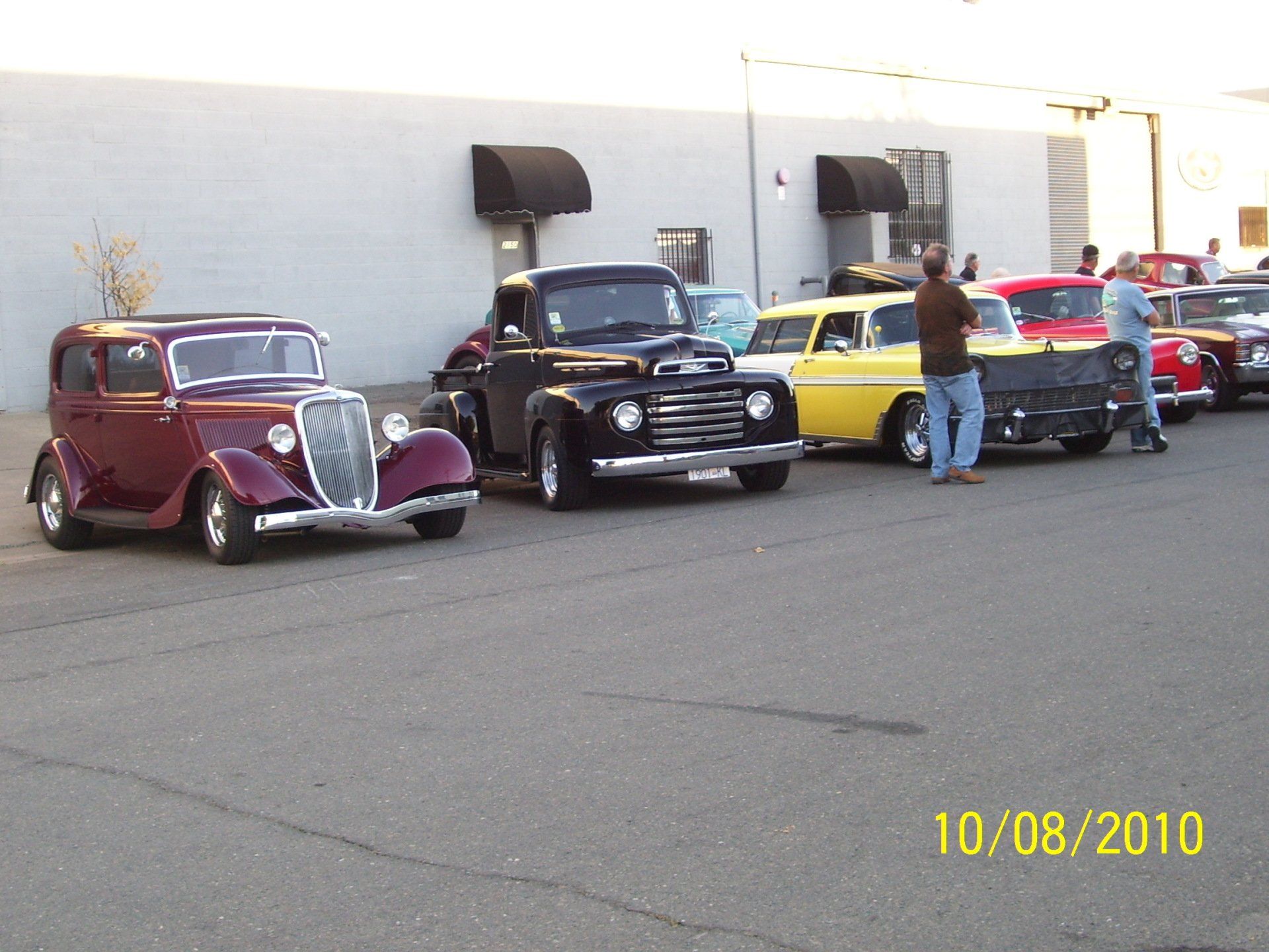A row of old cars are parked in front of a building on 10/08/2010