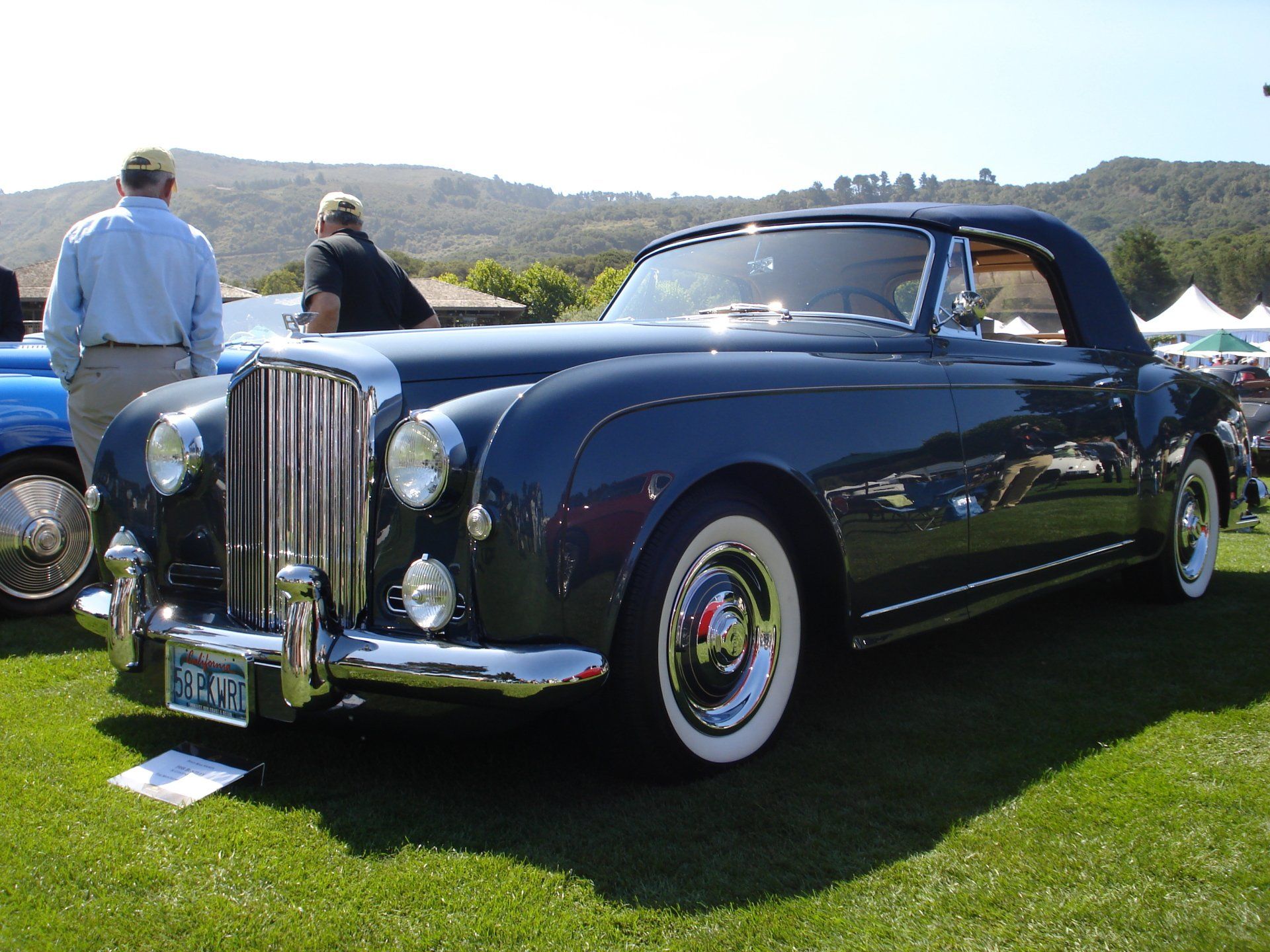 A black car with white tires is parked on the grass