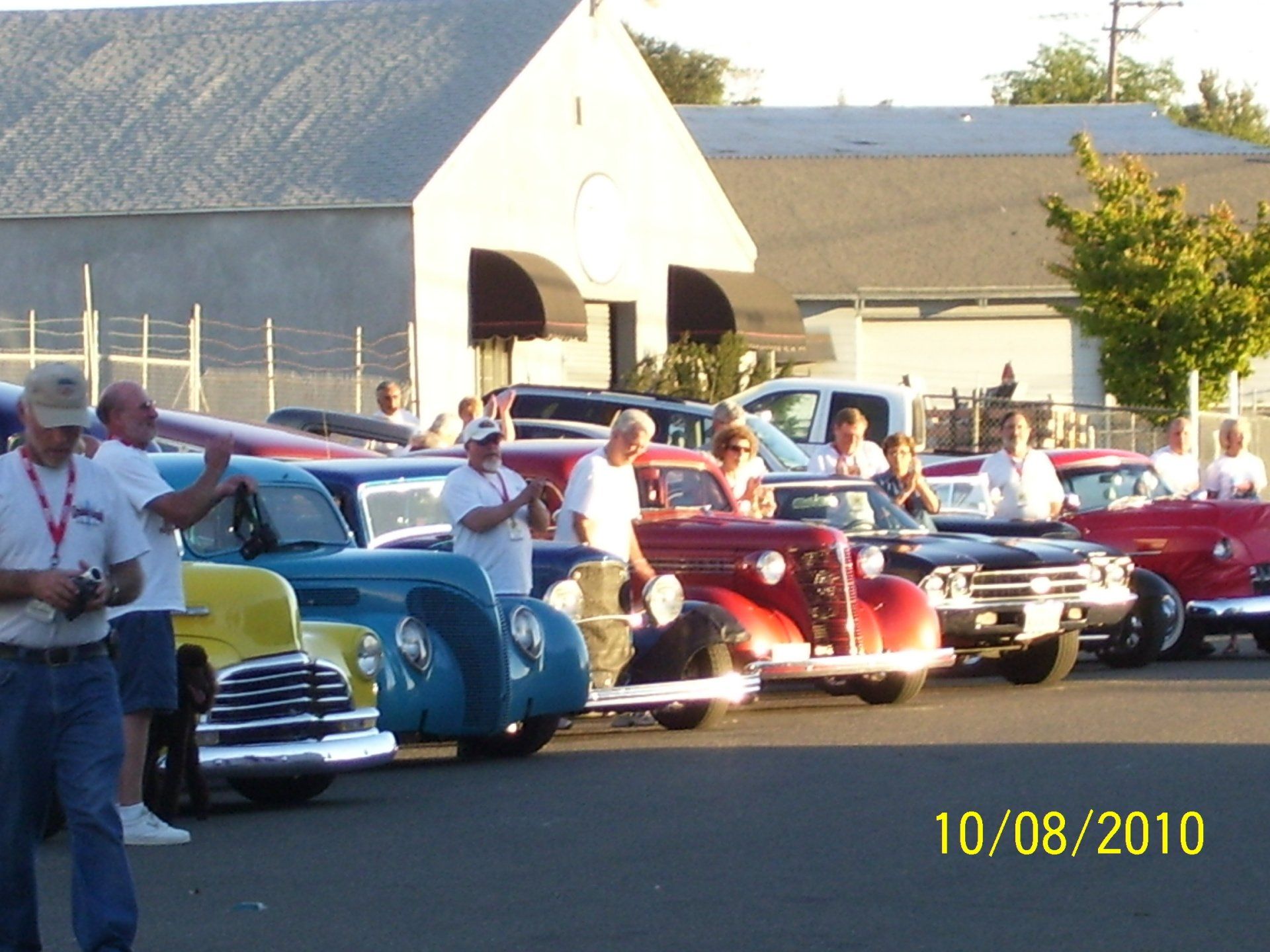 A group of old cars are parked in a parking lot on 10/08/2010