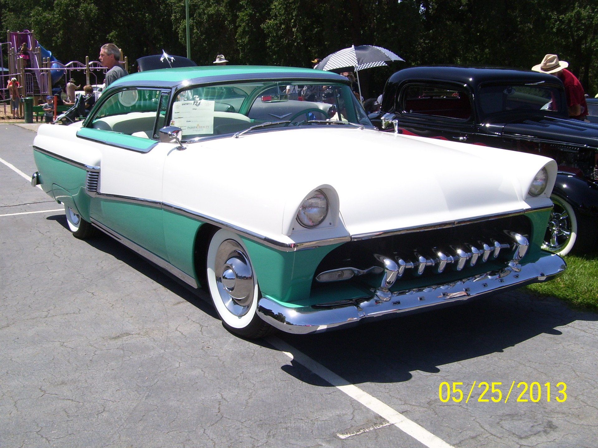 A green and white car is parked in a parking lot on 05/25/2013