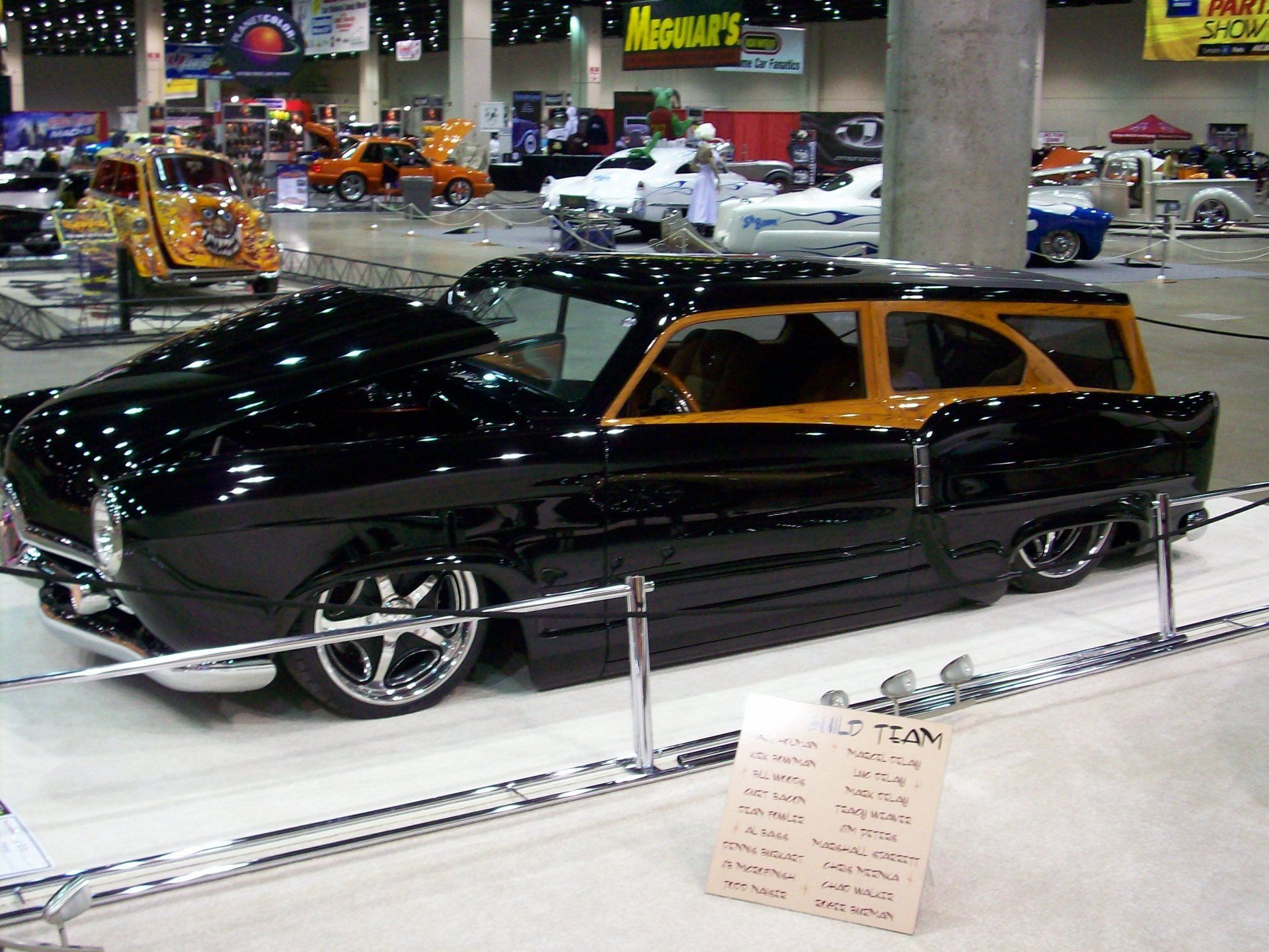 A black car with a wooden roof is on display at a car show