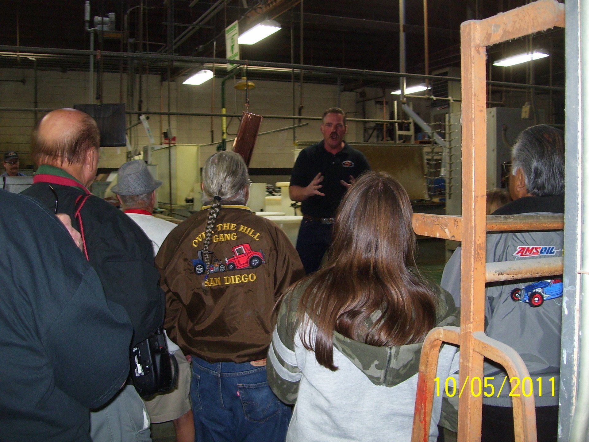 A group of people are standing in a room with a man wearing a jacket that says ' hollywood ' on it