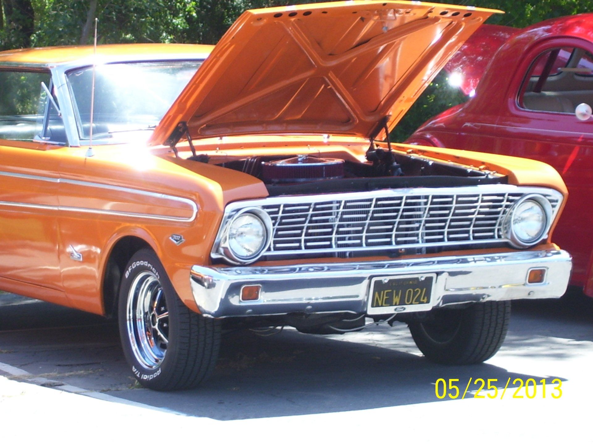 An orange car with the hood up has a new york license plate