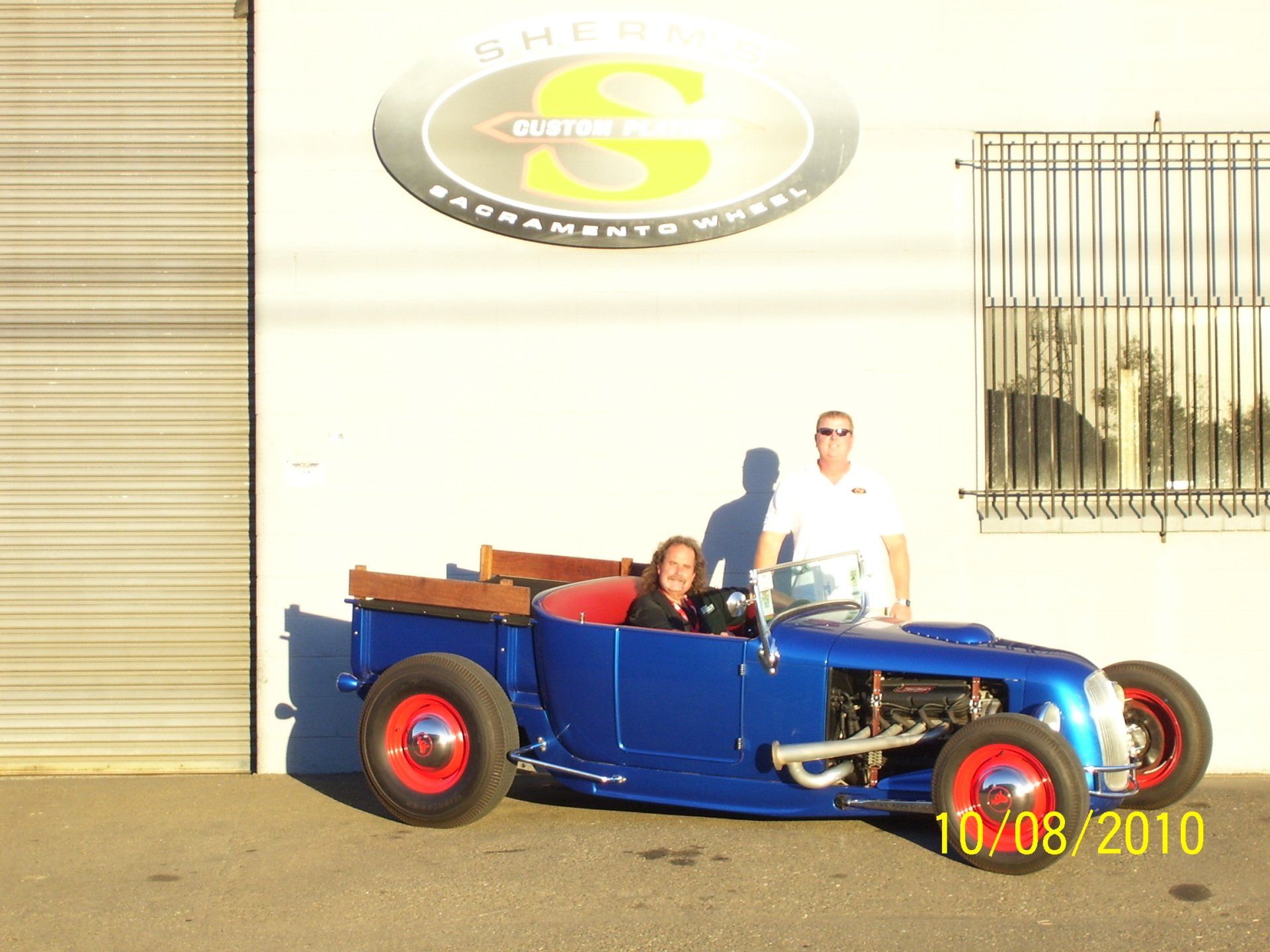 A couple standing next to a blue car with the date 10/08/2010