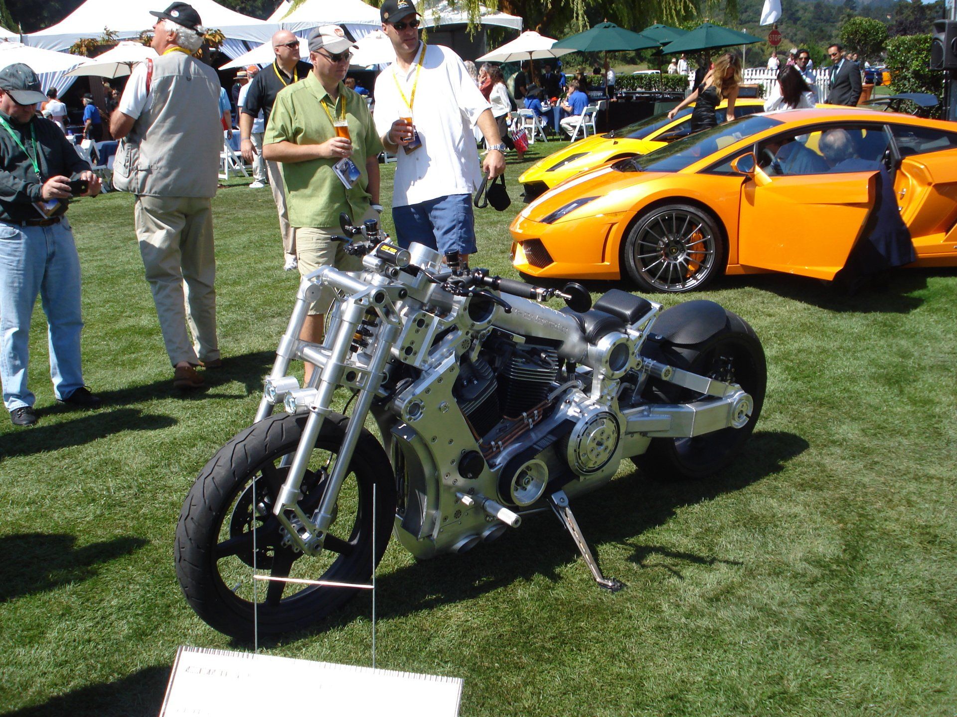 A motorcycle is parked in the grass in front of a lamborghini