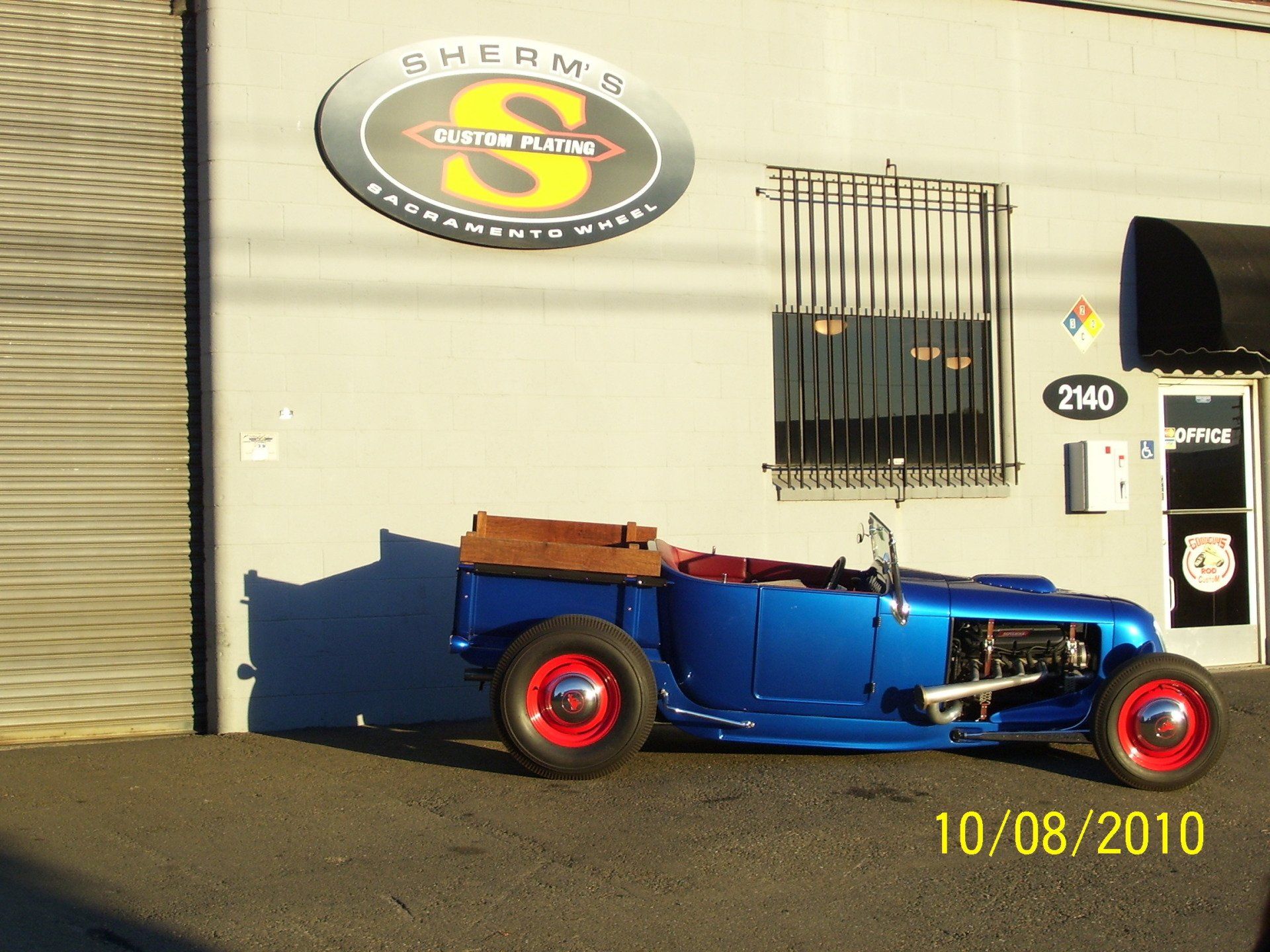 A blue car is parked in front of a store called sherm 's